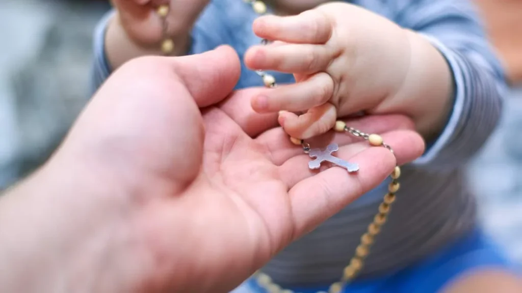 Imagem mao de mulher com mao de bebe segurando o terco do artigo Mulher do terço: 7 dicas para viver a Amoris Laetitia